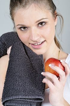 Young woman resting after exercise in fitness wear eating an apple