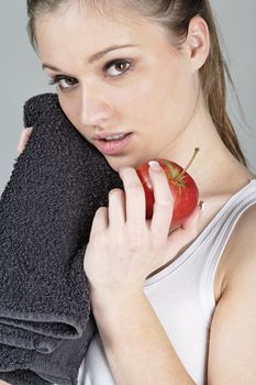 Young woman resting after exercise in fitness wear eating an apple