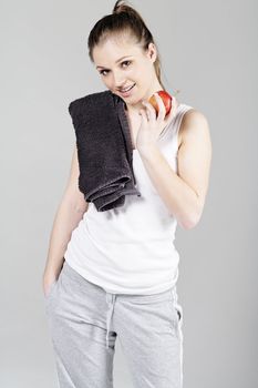 Young woman resting after exercise in fitness wear eating an apple