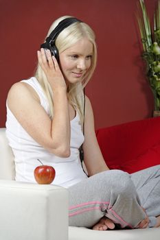 Young woman on sofa at home listening to music with headphones