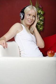Young woman on sofa at home listening to music with headphones