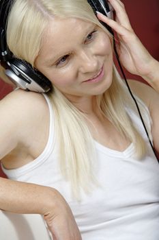 Young woman on sofa at home listening to music with headphones