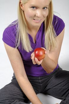 Young woman with an apple and resting after workout.