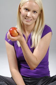 Young woman with an apple and resting after workout.