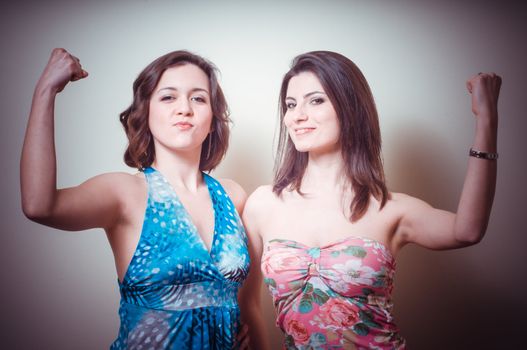 two beautiful girls showing muscle on gray background