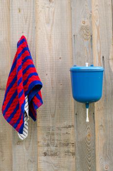 rural plastic hand wash tool and towel hang on wooden wall.