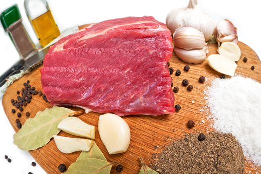 Fresh raw beef meat  on board with salt, pepper, garlic  and spices. close-up.