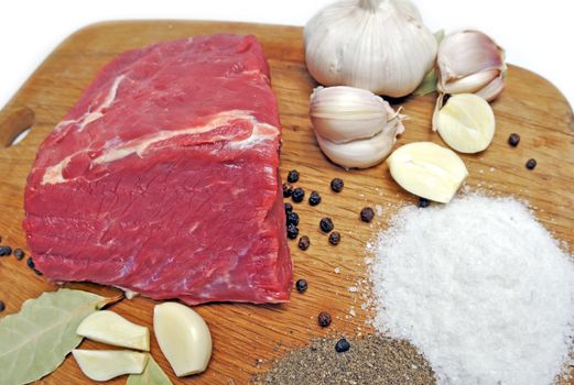 Fresh raw beef meat  on board with salt, pepper, garlic  and spices. close-up.