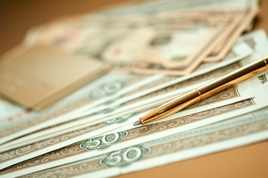 golden pen, money and bank card. closeup. shallow depth of field.