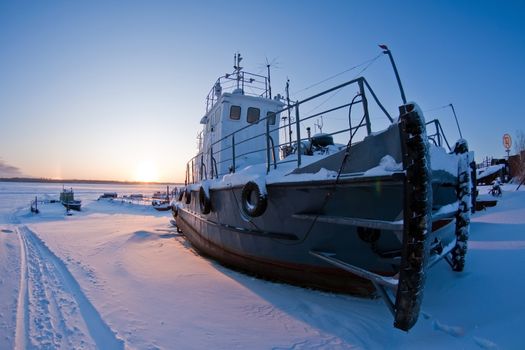 Ships covered with snow on coast Ob River, await  season of navigation. winter sunset, Siberia, Surgut city.