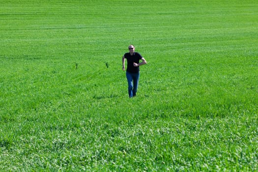 young man in sunglasses running in green field