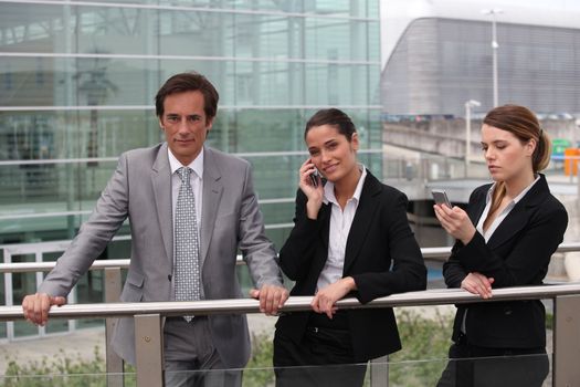 Businessmen and women on the phone outside.