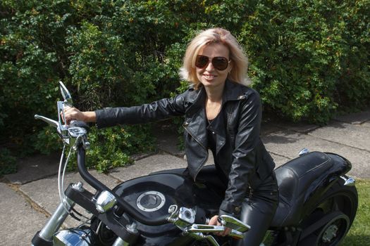 smiling biker girl dressed in leather clothes on a motorcycle