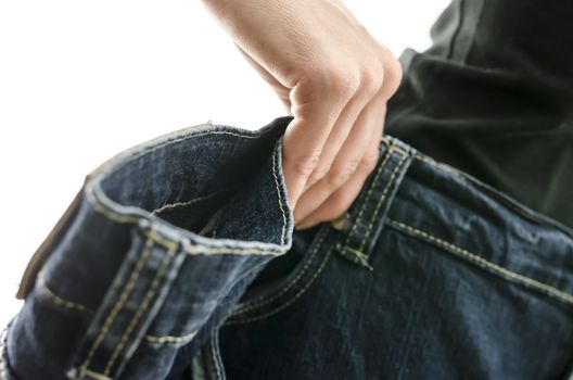 Detail of woman skinny waist in too large old jeans. Concept of successful dieting. Shallow dof.