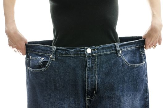 Woman showing how much weight she lost by wearing her old jeans. Weightloss concept.