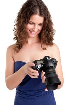 Woman holding an SLR camera and looking at the picture she took, isolated in white