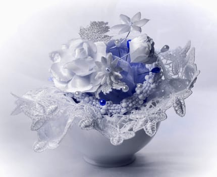 White flowers, lace and pins are in a white porcelain cup