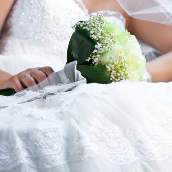 bouquet in the hands of the bride against the background of dress