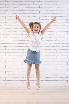 little girl in a jump near the white brick wall