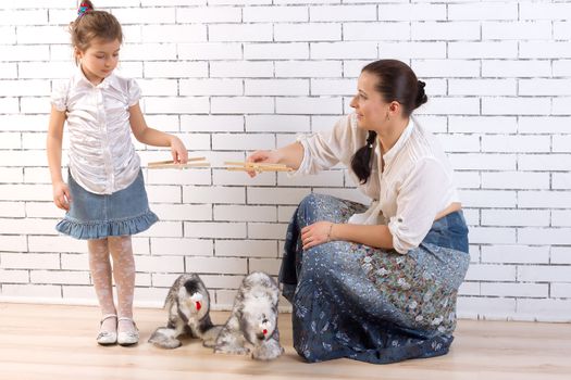 Mother and 5 year old daughter playing with two toy dogs