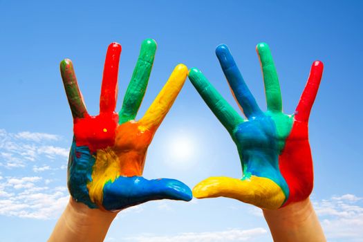 Painted hands, colorful fun. Creative, funny and artistic means happy! Blue sky background