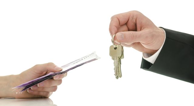 Closeup of male hand giving house keys to a woman in exchange for money. Concept of final step in purchasing a new house.