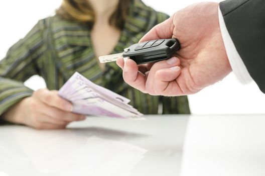 Woman giving money to a seller in exchange for key of her new car. 