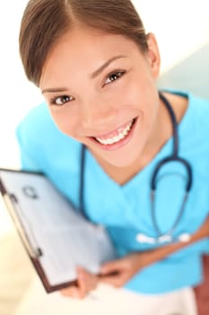 Nurse medical professional young doctor closeup portrait. Young multicultural female doctor wearing blue scrubs and stethoscope in high angle perspective view. Mixed race Asian Caucasian model.