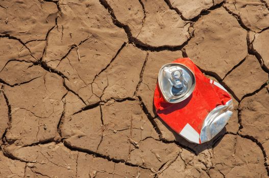 Thrown empty soda can on very dry soil