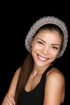 Asian woman modern hipster portrait smiling happy and confident looking at camera isolated on black background wearing knit hat. Multicultural Caucasian Asian female model in her 20s.