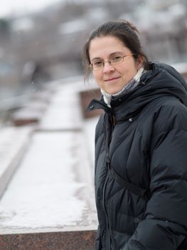 Woman standing near a wall in winter with snow