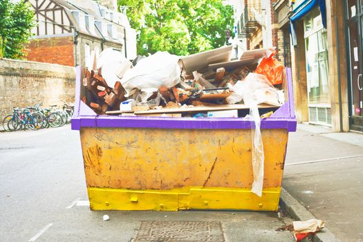 A waste skip in a town centre full of litter