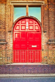 A large red double door in a victorian urban building in England