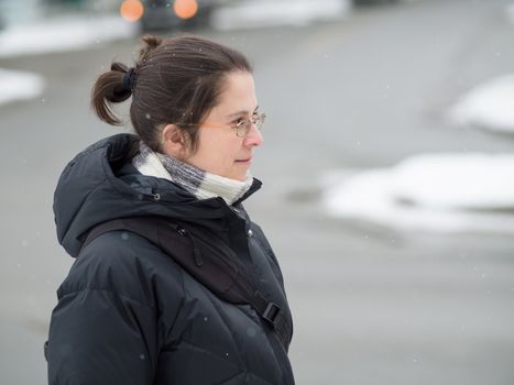 Woman walking in the street in winter while it snows