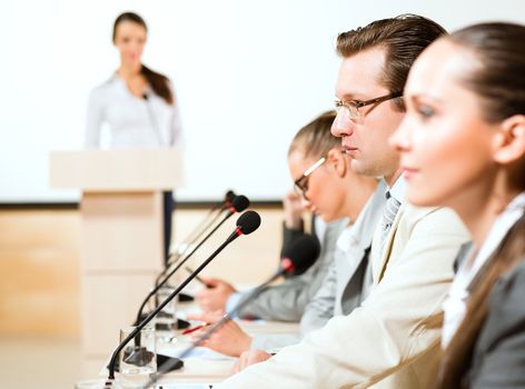 businessmen communicate at the conference, sitting at the table, on the table microphones and documents