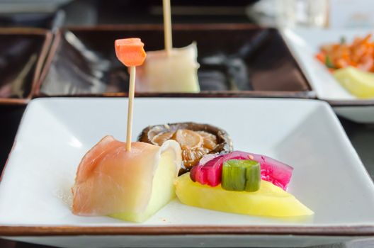 close up fish  and fruit sticks with  melon and mixed pickled vegetable on white dish