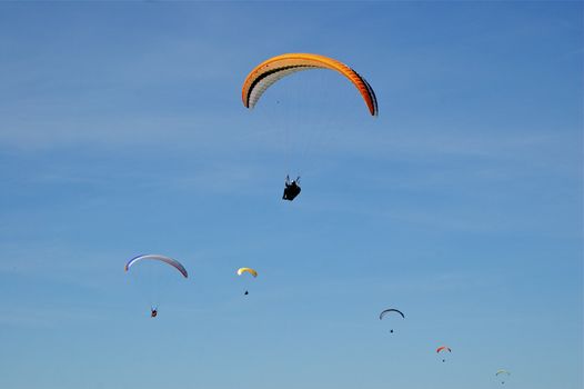 Formation of six Hang-Gliders in deep blue sky at different heights, sizes and colours with copy space.