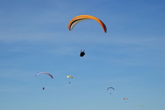 Formation of six Hang-Gliders in deep blue sky at different heights, sizes and colours with copy space.