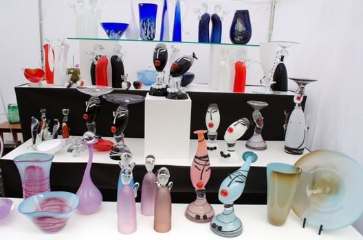 glass craft art vases and other dishes decor sale in outdoor street fair market.