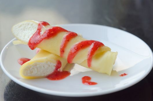 Dessert with the strawberries syrup and cream , the roll pancakes