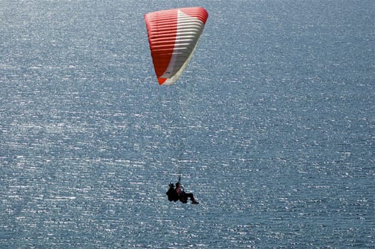 Hang-glider front and centre over ocean with copy space.