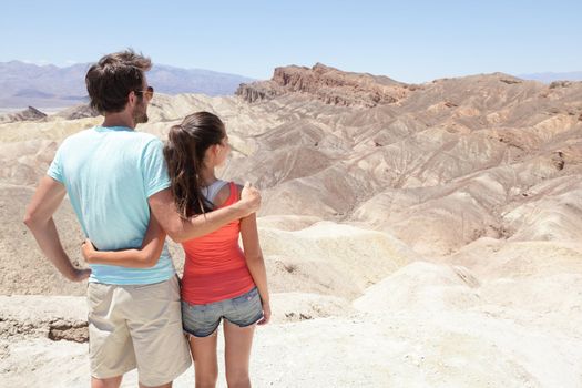 Death Valley tourists people in California enjoying view desert landscape of Zabriskie Point in Death Valley National Park, California, USA. Young couple on travel road trip in United States.