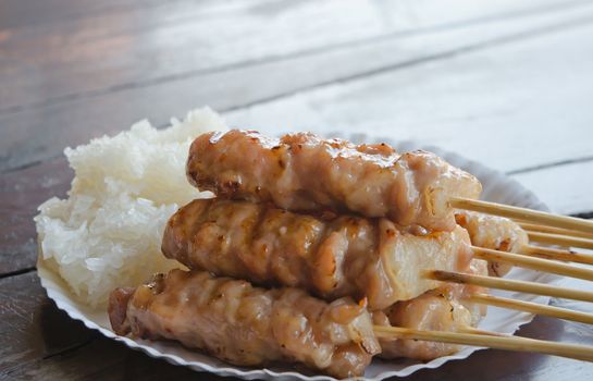 grilled pork and  sticky rice on paper plate , asian food