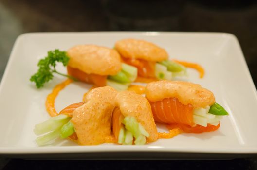 Roll made of salmon on white dish , japanese cuisine