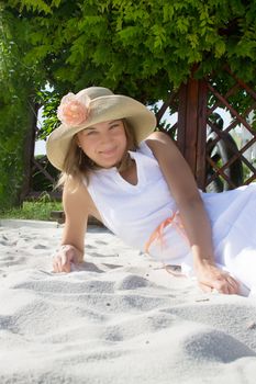 Woman with hat lying on white sand relaxing