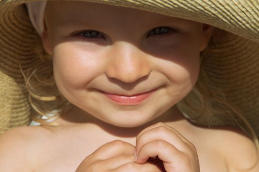 Adorable baby girl face sunlit under hat