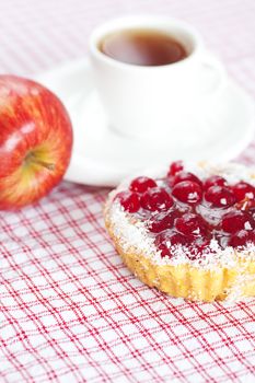 beautiful cake with berries,apple and tea on plaid fabric