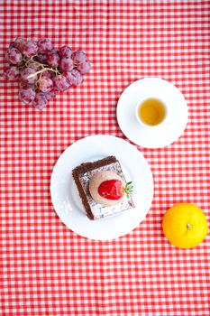 beautiful cake with strawberry,fruits and tea on plaid fabric