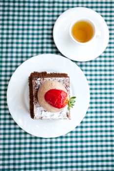 beautiful cake with strawberry and tea on plaid fabric