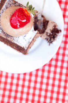 beautiful cake with strawberry on plaid fabric